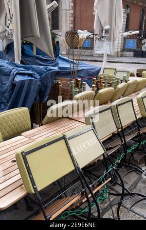 Gemäß den Einschränkungen der Regierung für die soziale Distanz von Covid werden Tische und Stühle eines geschlossenen Restaurantbetriebs "Laduree" während der dritten Sperre der Coronavirus-Pandemie am 3rd. Februar 2021 in London, England, auf der Covent Garden Piazza gestapelt und zusammengebunden. Stockfoto