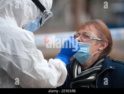 Malaga, Spanien. Februar 2021, 04th. Ein Gesundheitshelfer, der einen persönlichen Schutzanzug (PSA) trägt, sammelt Tauschproben von einer Frau außerhalb einer Coronavirus-Teststation während eines massiven covid-19-Tests am Plaza Limeno in der Innenstadt. Aufgrund der hohen Rate von Coronavirus-Infektionen in der Hauptstadt Málaga werden etwa 1,600 freiwillige Personen von den Gesundheitsbehörden ausgewählt, um an einem zufälligen Antigencovid-19-Test teilzunehmen. Kredit: SOPA Images Limited/Alamy Live Nachrichten Stockfoto