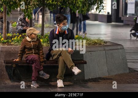 BELGRAD, SERBIEN - 20. OKTOBER 2020: Asiatische Familie, ein Vater und sein Sohn, Junge, sitzen auf einer Bank mit Gesichtsmaske Schutzausrüstung auf Coronaviru Stockfoto