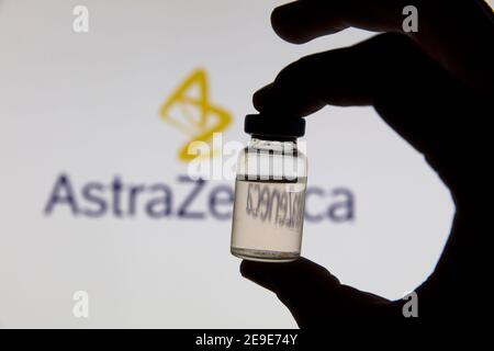 OXFORD, Großbritannien - Februar 2020: Covid-Impffläschchen vor dem AstraZeneca-Logo Stockfoto