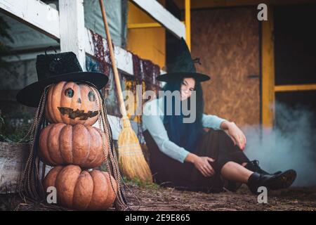 Im Vordergrund ist eine Figur von Kürbissen mit einem bösartigen Gesicht, im Hintergrund sitzt eine Hexe Stockfoto