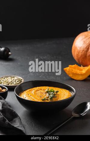 Gesunde Kürbissuppe mit knusprigen Croutons auf schwarz. Nahaufnahme. Vertikales Format. Stockfoto