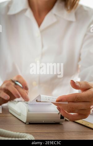 Buchhalterin mit Hinzufügen Maschine während der Arbeit an der Firma Papierkram. Stockfoto