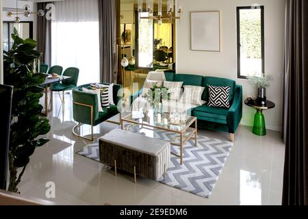 Modernes skandinavisches Wohnzimmer mit dunkelgrünem Sofa, Design Kommode, Blatt in Vase, gemütliches Kissen und elegante Accessoires. Vorlage. Stilvolles h Stockfoto