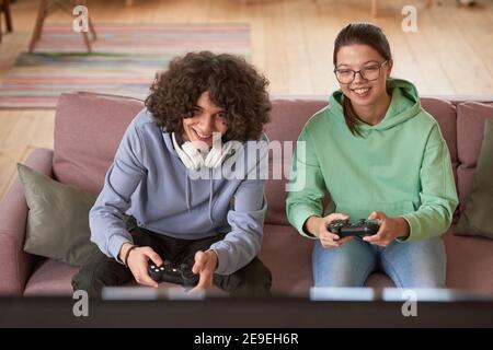 Zwei Freunde sitzen auf dem Sofa und spielen zusammen in online Videospiel zu Hause Stockfoto