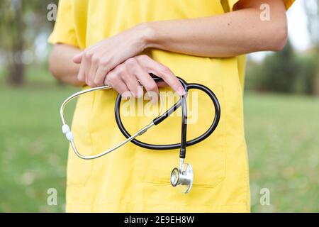 Nahaufnahme der Hände einer Krankenschwester, die ein Stethoskop hält. Sie ist draußen. Stockfoto