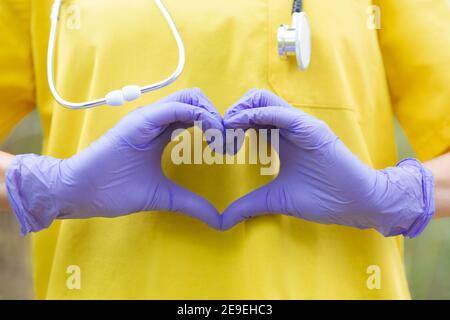 Nahaufnahme nicht erkennbares Gesundheitspersonal mit Uniform, Handschuhe und Stethoskop bilden mit den Händen ein Herz. Gesundheitskonzept. Stockfoto