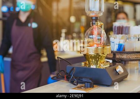 Nahaufnahme des Barista Machen Sie Kaffee mit dem Vacuum Pot Syphon Brewer. Syphon (Siphon) Kaffeemaschine bereitet Getränk mit zwei Kammern, wo Dampfdruck und V Stockfoto