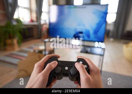Nahaufnahme des Spielers, der den Joystick hält und Videospiel anspielt Großer Fernseher zu Hause Stockfoto
