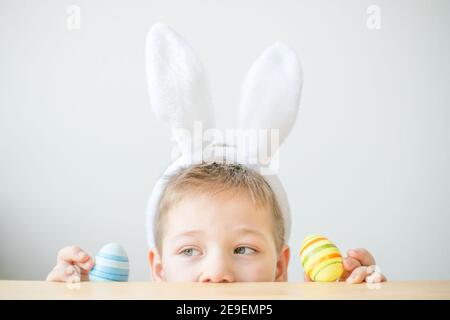 Portrait von lächelnden Jungen mit Hasen Ohren halten farbige Eier für Ostern in Kunststudio, Kopierer Raum. Vorbereitung auf Ostern. Stockfoto