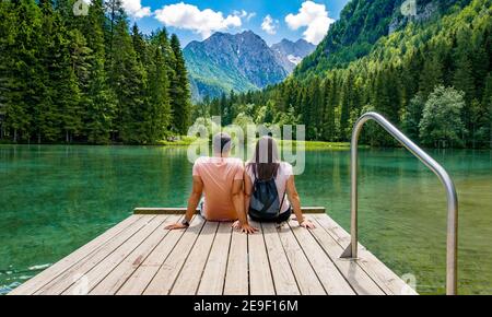 Junges Coupl auf Deck am wunderschönen See in den Bergen sitzen. Zgornje Jezersko, Slowenien Stockfoto