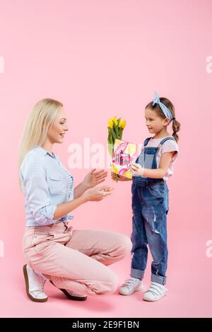 Glückliche Mutter erhält Geschenke von Tochter auf rosa Stockfoto