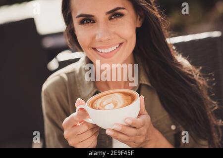 Foto-Porträt von positiven Mädchen genießen Kaffee mit Latte Kunst Sitzen im Café im Freien Stockfoto