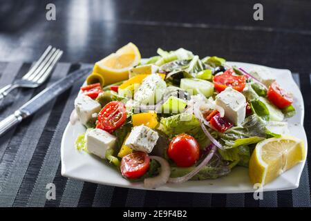 Nahaufnahme Gemüsesalat mit Tomaten, Käse, Zitrone und Oliven auf einem Teller Stockfoto