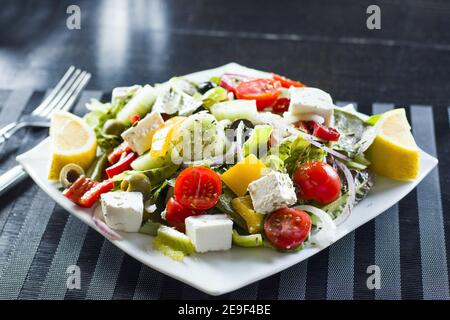 Nahaufnahme Gemüsesalat mit Tomaten, Käse, Zitrone und Oliven auf einem Teller Stockfoto