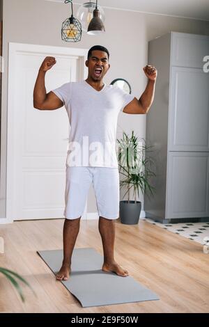 Porträt eines afroamerikanischen Mannes, der mit aufhebenden Händen schreit und nach dem Training die Kamera anschaut. Stockfoto