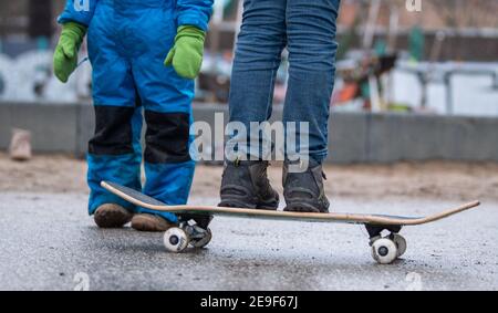 Berlin, Deutschland. Februar 2021, 04th. Zwei Kinder stehen in der Nähe eines Spielplatzes in Berlin. Ein Kind balanciert auf einem Skateboard. Aufgrund der Coronavirus-Pandemie sind Kindertagesstätten und Schulen geschlossen. Quelle: Dorothée Barth/dpa/Alamy Live News Stockfoto