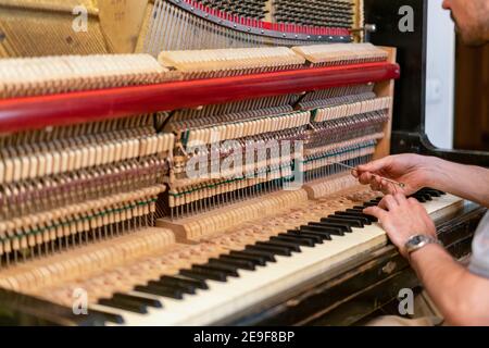 Ein altes Klavier aufsetzen. Der Meister repariert ein altes Klavier. Tief Reinigung des Klaviers. Getönt Stockfoto