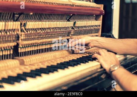 Ein altes Klavier aufsetzen. Der Meister repariert ein altes Klavier. Tief Reinigung des Klaviers. Getönt Stockfoto