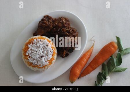 Carrot puttu, eine Vielzahl von Kerala Reis Dampfkuchen durch Hinzufügen zerkleinert Karotten serviert zusammen mit Huhn Braten in Kerala-Stil mit Kokosöl zubereitet Stockfoto