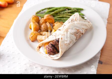 griechischer Hamburger gerollt in einem Fladenbrot mit fingerling Pota Stockfoto