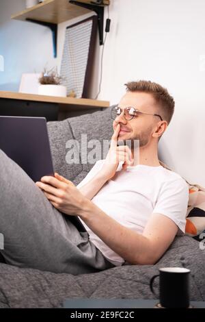 Junge kaukasischen Mann Programmierer sitzen auf Sofa Video anrufen Remote-Freund Frau im Online-Webcam-Chat auf Laptop zu Hause im Büro sprechen. Distanz-Datierung Stockfoto
