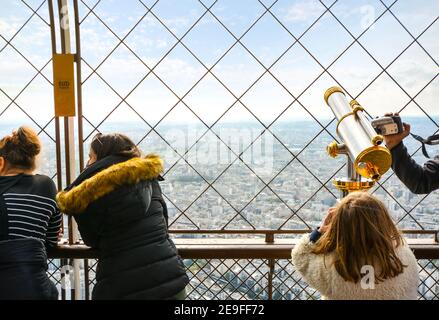 Touristen genießen den Blick von der ersten Plattform des Eiffelturms neben einem Teleskop, in Paris, Frankreich. Stockfoto