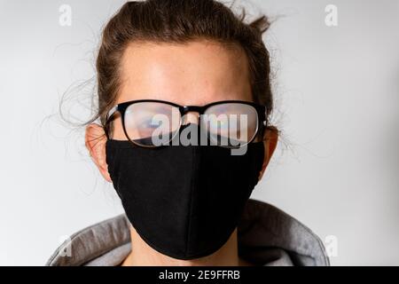 Junger Mann mit nebliger Brille, verursacht durch das Tragen einer Schutzmaske. Schutzmaßnahme während einer Coronavirus-Pandemie Stockfoto