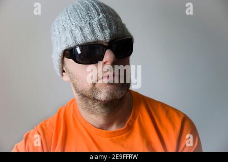 Porträt eines Mannes in Sonnenbrille und Winterhut Stockfoto