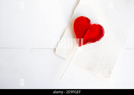 Rotes Herz Lollipop auf weißem Tischhintergrund. Süßigkeiten. Liebeskonzept. Valentinstag. Stockfoto