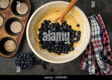 Heidelbeeren werden dem Teig hinzugefügt, um Blaubeer-Muffins zu machen Stockfoto