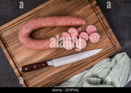 Frische polnische Kielbasa wird mit einem Messer auf einem geschnitten Schneidebrett Stockfoto