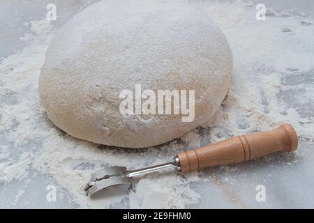 Frisch auferstandener klassischer französischer Boule Brotteig auf einer Marmorplatte mit einem Lahmen, der sich zum Scoring bereit macht Stockfoto