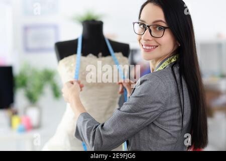 Weibliche Stylistin steht neben Schaufensterpuppe tragen Hochzeitskleid Stockfoto