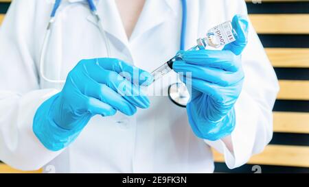 Der Arzt füllt eine Spritze mit dem Impfstoff COVID-19. Vorbereitung auf die Impfung. Testen eines Impfstoffs gegen eine Coronavirus-Infektion. Ein Arzt hält Stockfoto