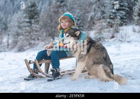 Winterkinder. Kleiner Junge mit Hund, der Spaß im Schnee hat. Winter Grußkarte, Banner, Poster. Thema Weihnachtsferien Winter Neujahr. Stockfoto