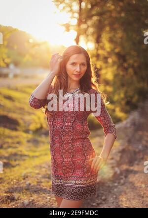 Porträt der jungen Frau in lässigen Sommerkleid, starke Sonnenuntergang Hintergrundbeleuchtung mit schönen Bokeh Stockfoto