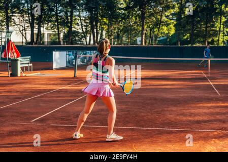 Blick von der Rückseite einer jungen Frau, die Tennis zahlt Auf einem Platz draußen Stockfoto