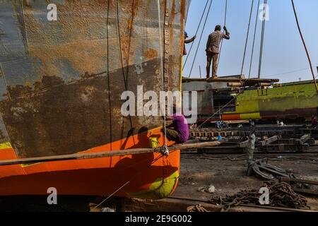 Hafenarbeiter führen Wartungsarbeiten am Rumpf eines Schiffes am Ufer des Buriganga Flusses durch.Flüsse sind das Lebenselixier der Delta-Nation von 168 Millionen Menschen, in der ein Großteil des tief liegenden Landes mit dem Boot erreicht wird. Angesichts des starken Wirtschaftswachstums in Bangladesch in den letzten Jahren wurden mehr Investitionen in neue und größere Schiffe getätigt. Achtundzwanzig Werften, die 30,96 Hektar des Buriganga-Vorhores besetzen, sind in den letzten 50 Jahren ohne Genehmigung oder Richtlinien in Betrieb, verschmutzen den Fluss und greifen in das Flussufer ein, wodurch seine Schiffbarkeit verringert wird. Stockfoto