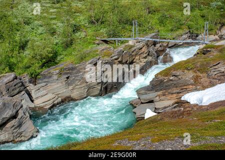 Hängebrücke in den Bergen über schnell fließenden, turbulenten Fluss im Padjelanta Nationalpark in Lappland, Schweden. Stockfoto