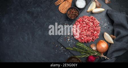 putenfleisch mit Pfeffer, Zwiebel und Rosmarin auf schwarzem Betongrund gemahlen. Stockfoto