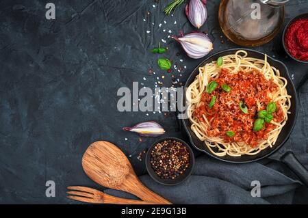 Klassisches italienisches Gericht Pasta Bolognese mit Basilikum auf dunklem Hintergrund. Kochkonzept. Stockfoto