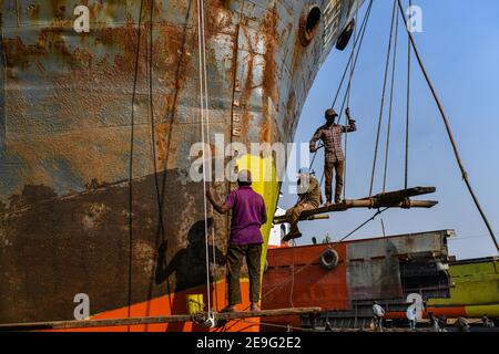 Hafenarbeiter führen am 4. Februar 2021 Wartungsarbeiten am Rumpf eines Schiffes am Ufer des Buriganga-Flusses in Dhaka, Bangladesch, durch. Stockfoto