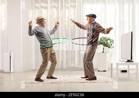 Lustige ältere Männer drehen Hula Hoops in einem Raum Stockfoto