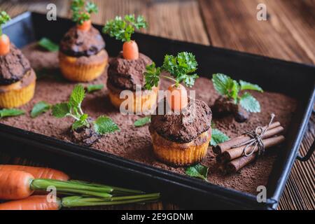 Süße Karotten-Muffins mit Kokosnuss und Schokoladencreme, bestreut mit Kakaopulver Stockfoto