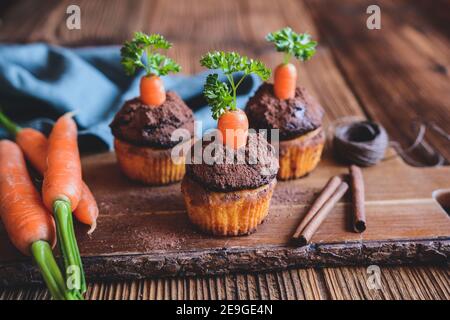 Süße Karotten-Muffins mit Kokosnuss und Schokoladencreme, bestreut mit Kakaopulver Stockfoto
