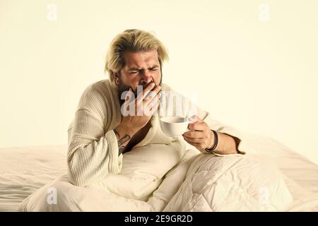 Der Körper wurde von wesentlichen Komponenten für eine gute Gesundheit und Energie beraubt. Start Tag mit gutem Kaffee. Gourmet-Espresso. Genießen Sie den morgendlichen Kaffee. Schöner Mann trinkt Kaffee. Reifer bärtiger Mann im Bett. Stockfoto