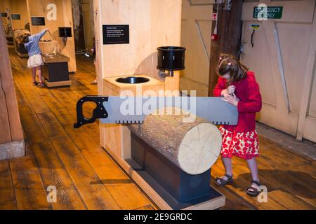 Junges Mädchen / Kind / Kinder / Kind / Kinder / Tourist Interagieren und spielen mit interaktivem Holz und Holz für Masten für Schiffe, zeigen und zeigen Teil der "Command of the Ocean Gallery" in den Historic Dockyards in Chatham, Kent UK (121) Stockfoto