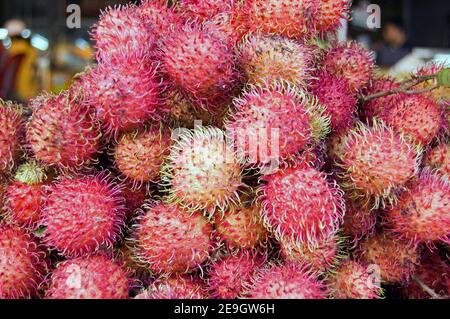 Ein Haufen reifer Rambutanfrüchte - lateinischer Name nephelium lappaceum - auf einem Marktstand in Kambodscha. Stockfoto