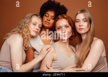 Junge hübsche kaukasische, afro, skandinavische Frau posiert fröhlich zusammen auf braunem Hintergrund, Lifestyle diverse Nationalität Menschen Konzept Stockfoto
